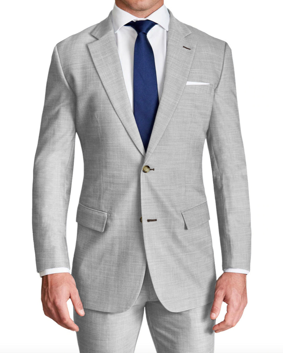 A man wearing a lightweight heathered light grey stretch suit with a two-button single-breasted blazer and matching trousers, paired with a white shirt and a blue tie.