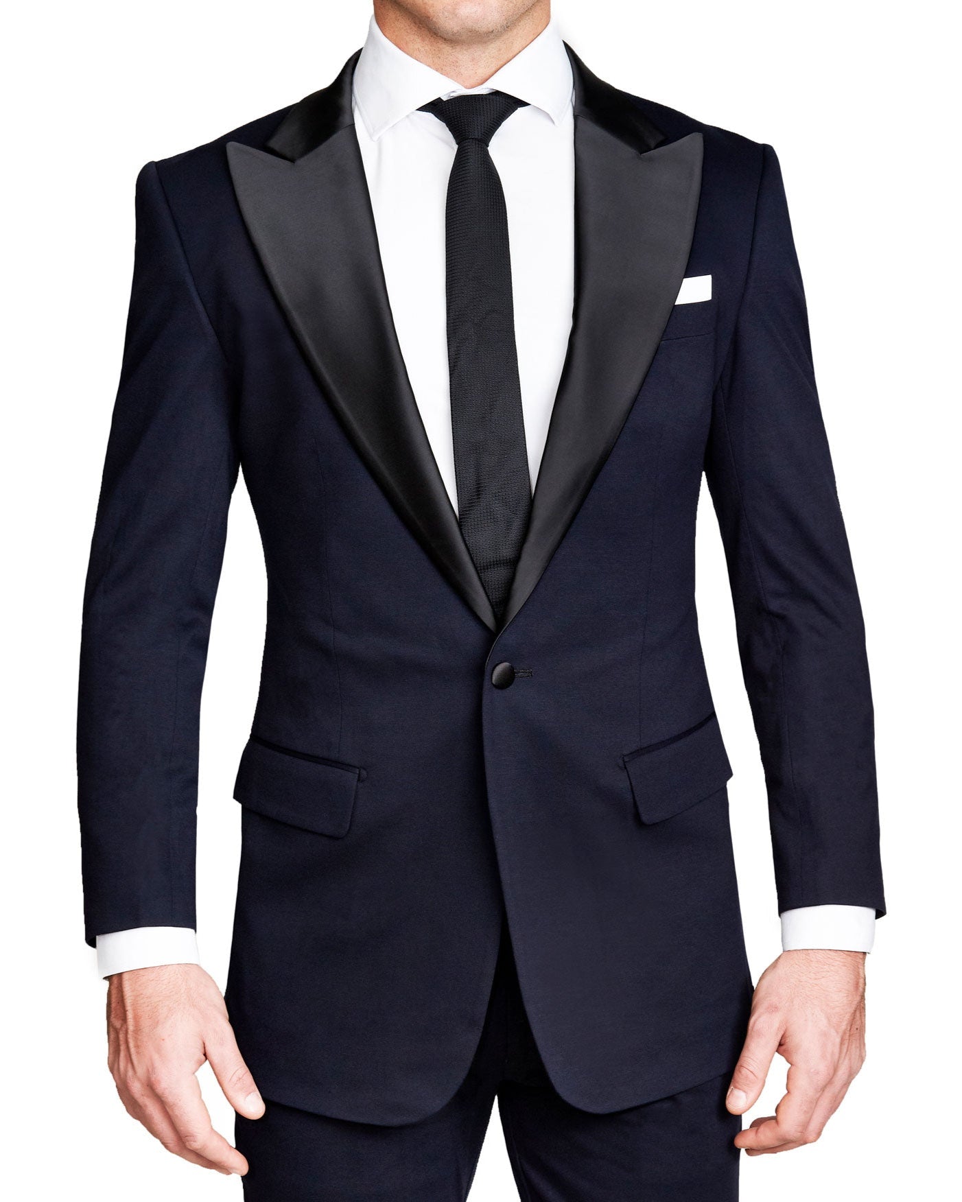 A man wearing a solid navy tuxedo with a peak lapel, black satin-covered buttons, and a double vent.