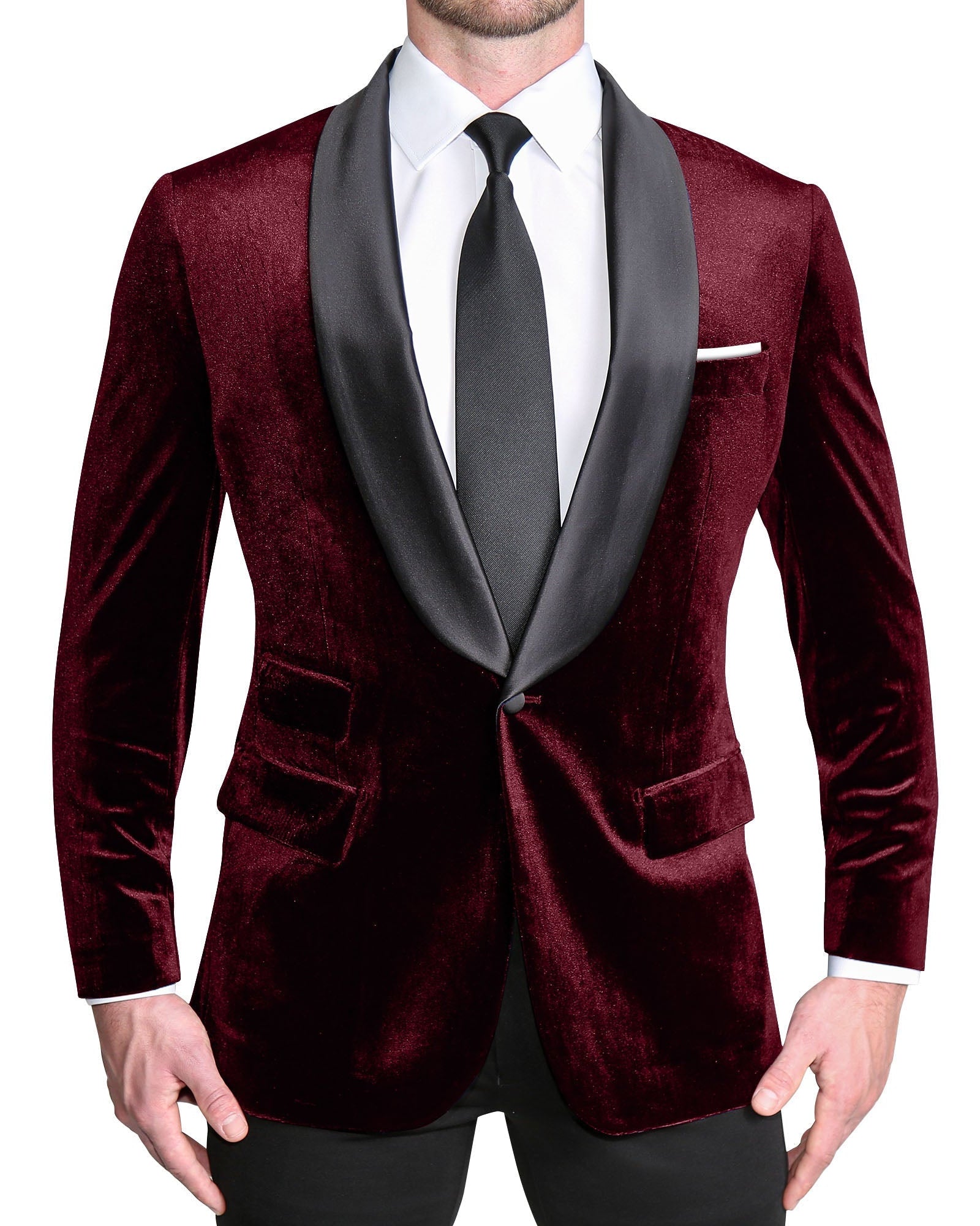 A person wearing a maroon velvet tuxedo with a single-breasted jacket and shawl lapels, paired with black trousers and a dark shirt.
