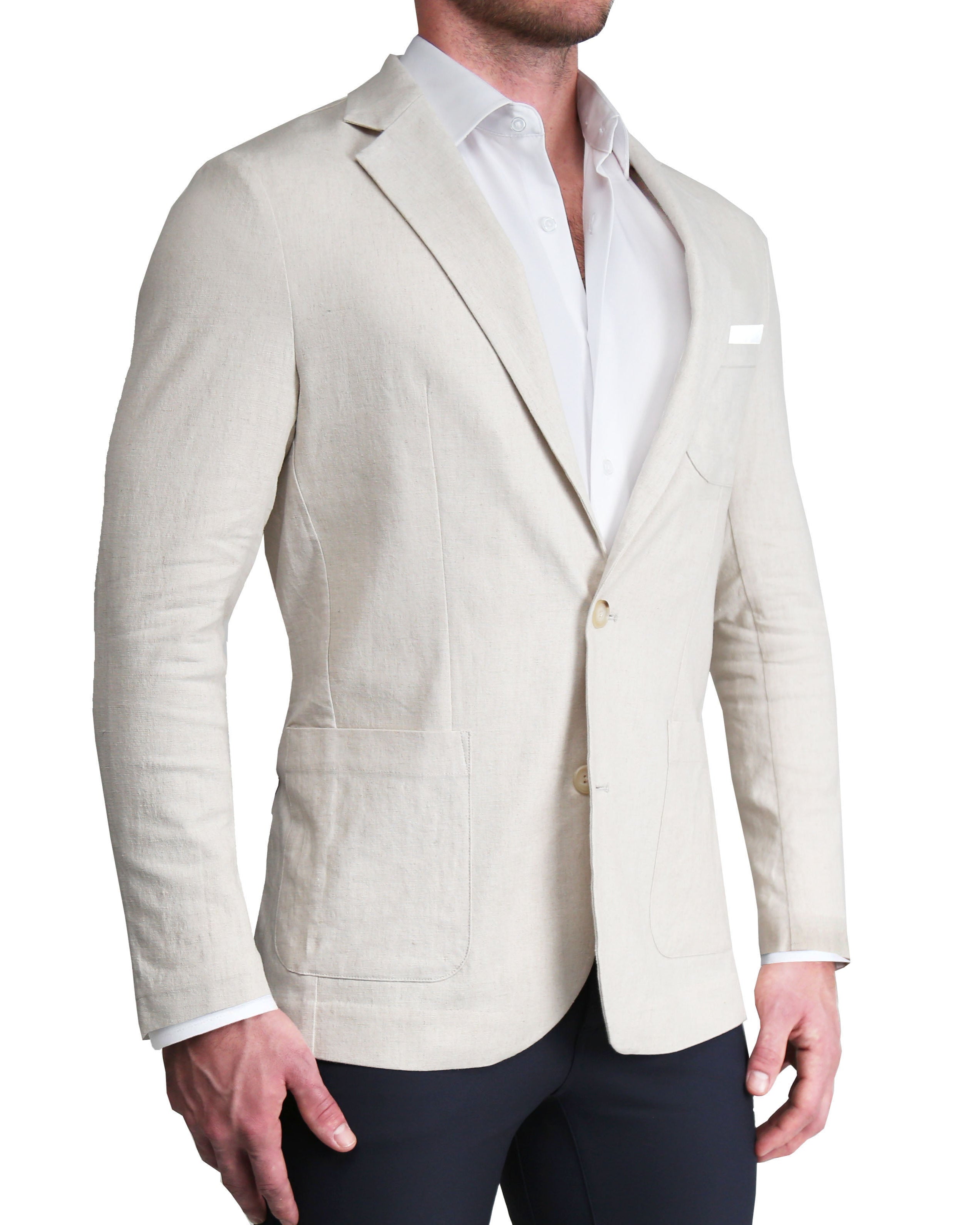 A man wearing a beige unstructured linen blazer with patch pockets, a white shirt, and dark trousers.